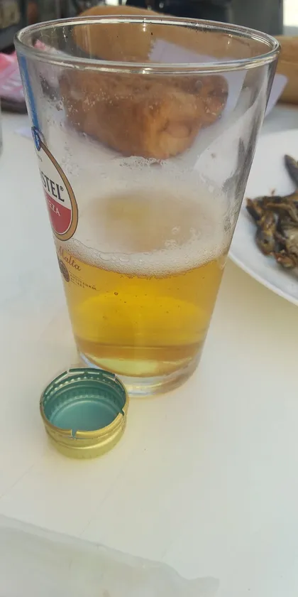 Una birra a medias con el bocata al trasluz y un plato de pescaditos fritos