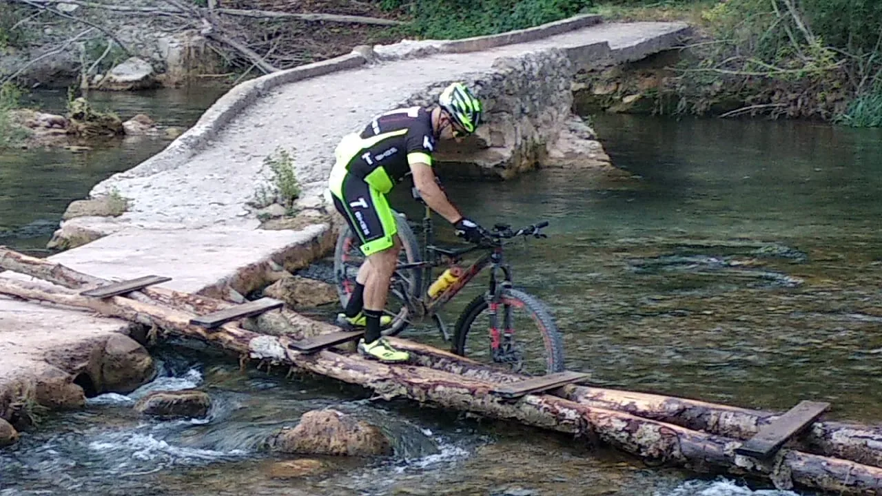 Un ciclista de chaleco fluorescente sobre la pasarela de troncos