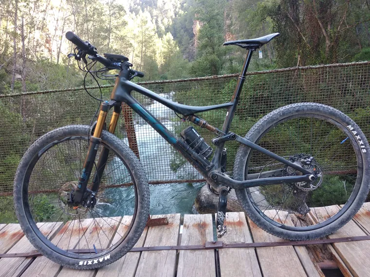 Una MTB doble sobre el puente colgante con el río turquesa debajo