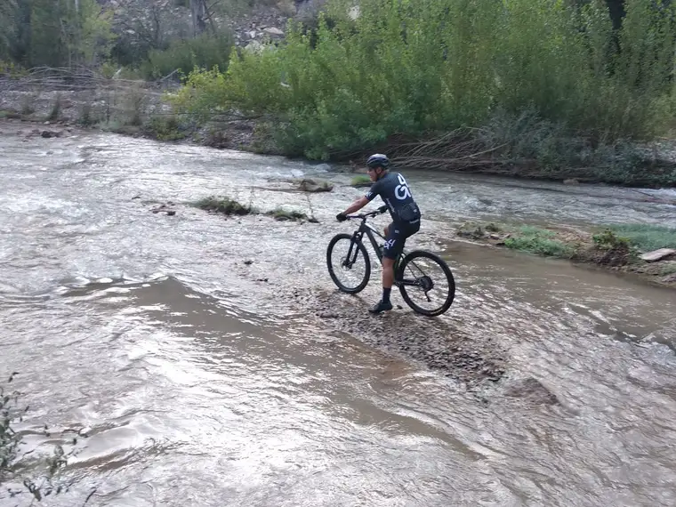 Un ciclista parado al borde de la lámina de agua del azud
