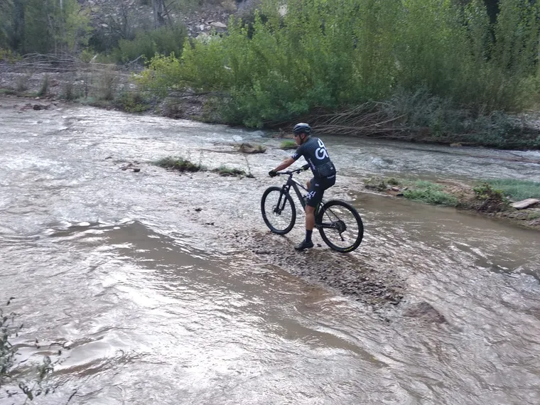 Un ciclista parado al borde de la lámina de agua del azud