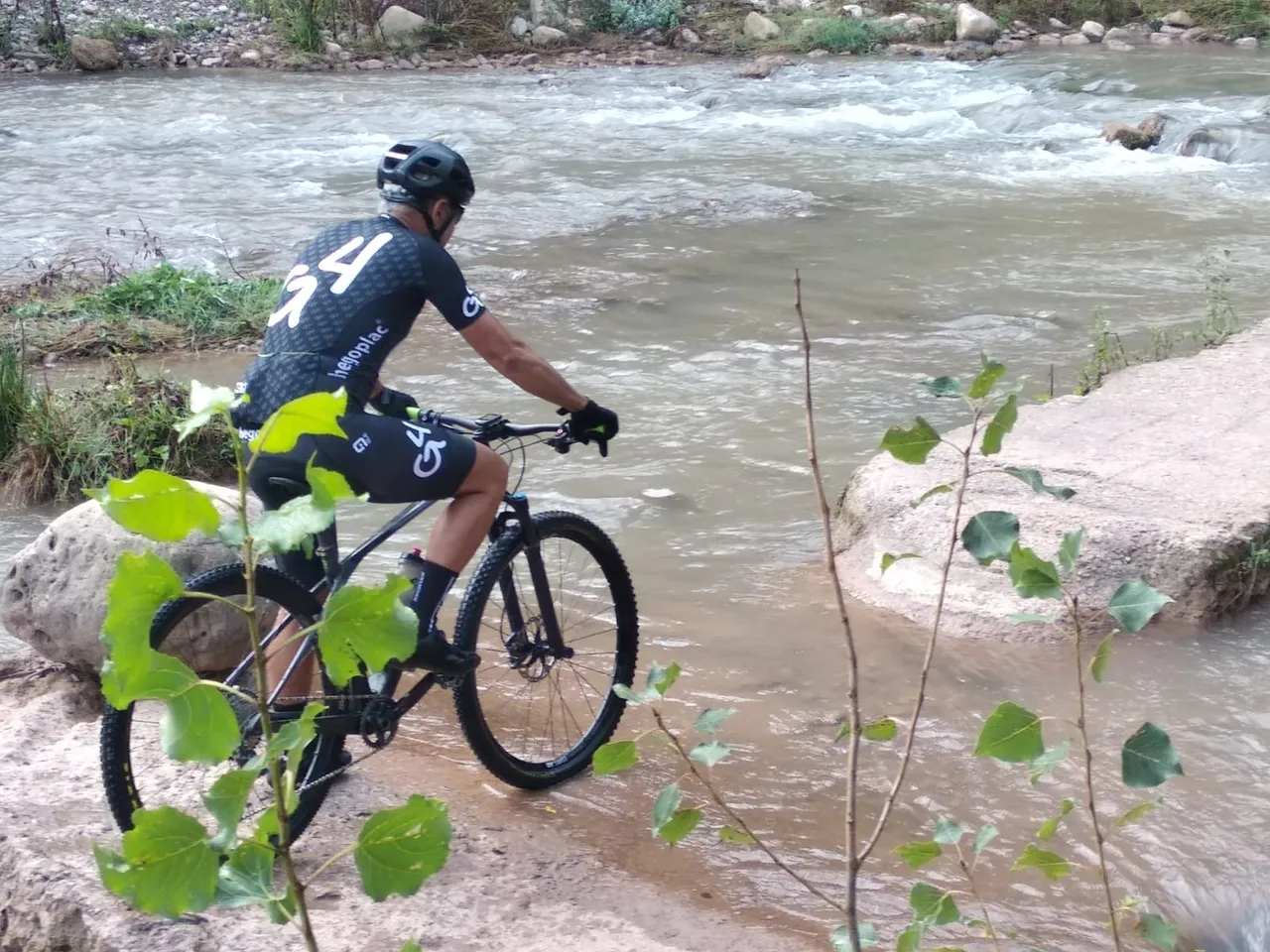Un ciclista de perfil rodando por la roca junto al rápido
