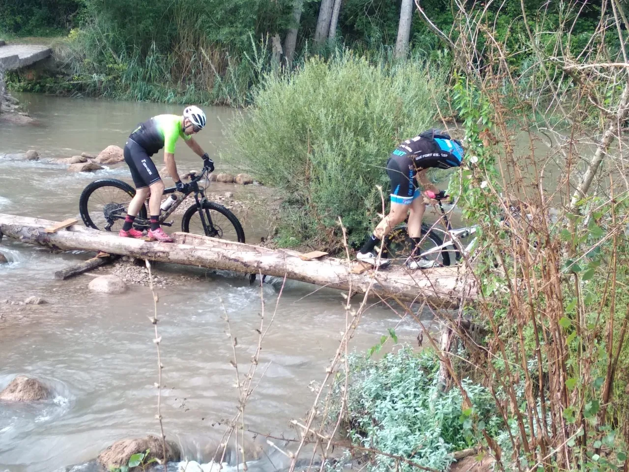 Dos ciclistas porteando la bici sobre la pasarela