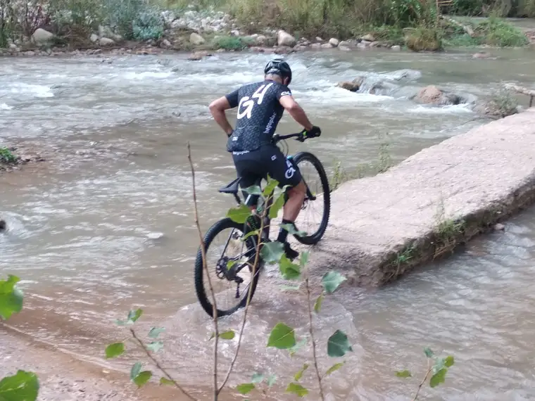 Un ciclista bajando por la roca hacia el vado del río