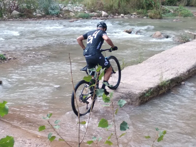 Un ciclista bajando por la roca hacia el vado del río