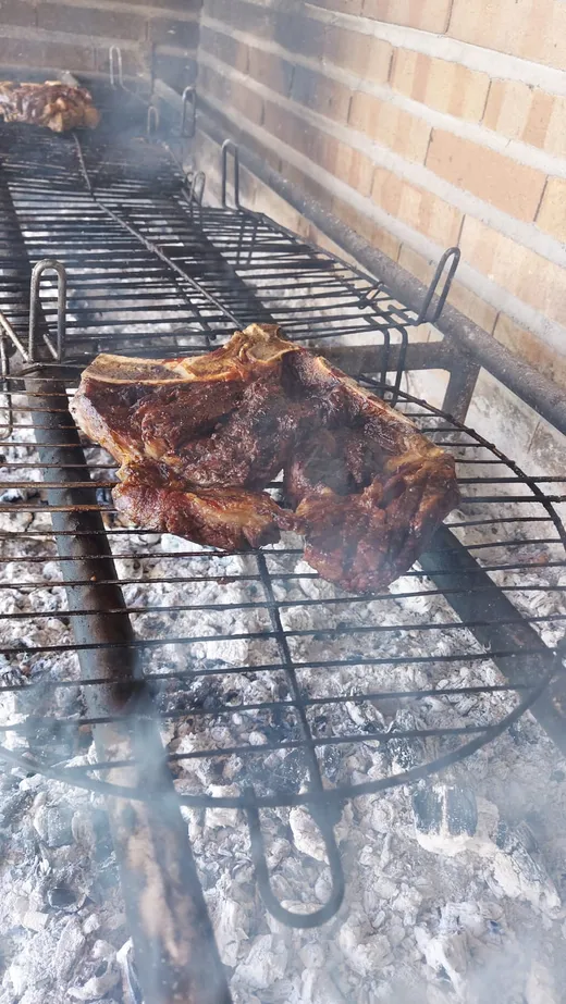 Un chuletón sobre la parrilla entre humo y brasas