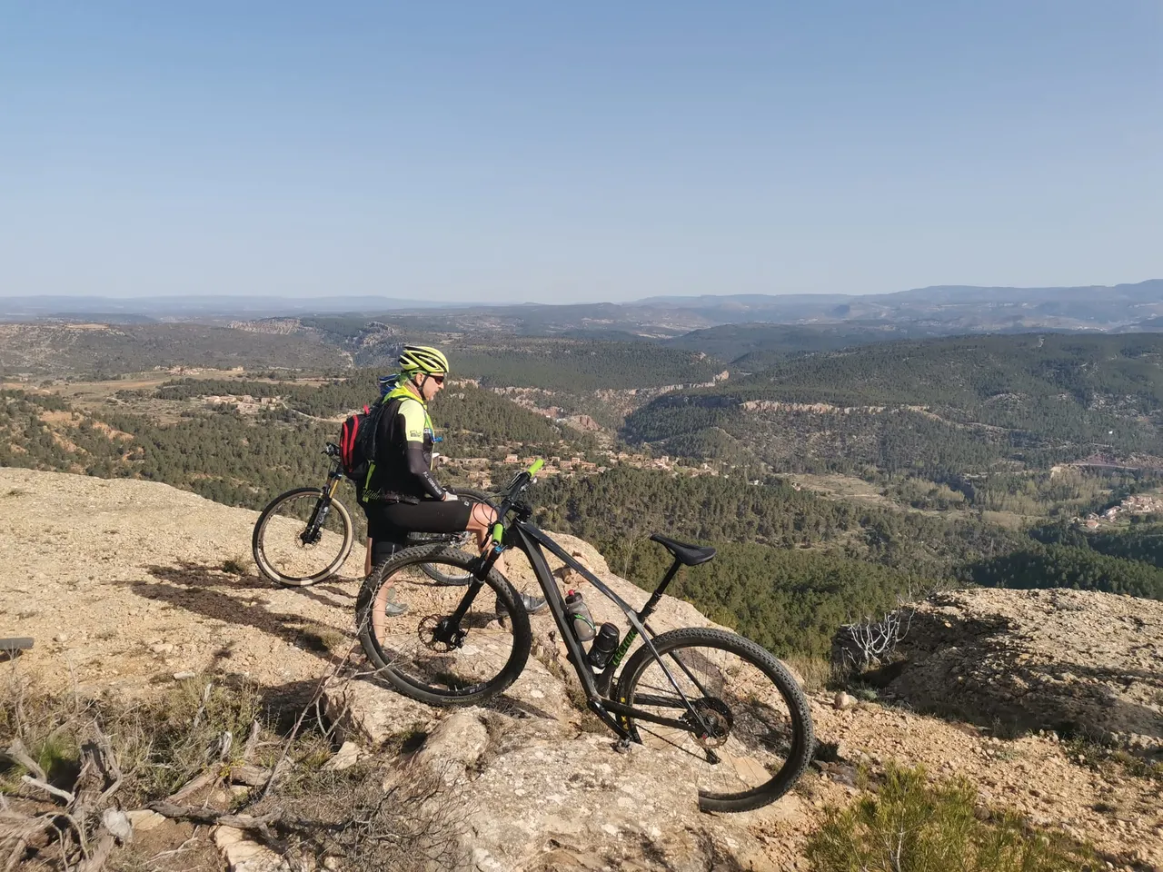 Un ciclista con su MTB en el cortado, con el pueblo abajo