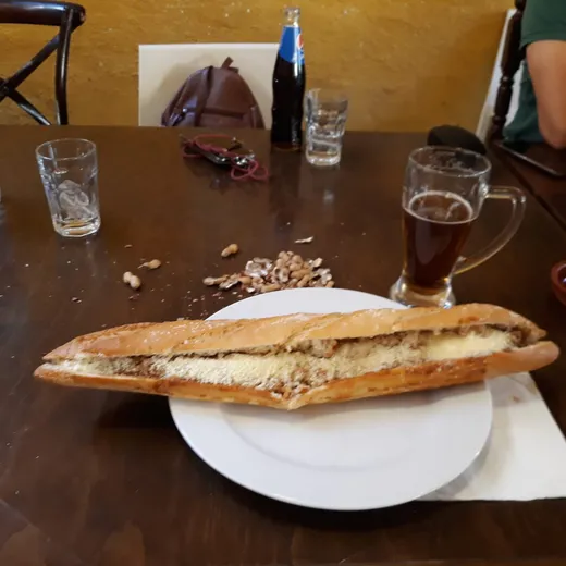 Un bocata enorme con cerveza en la mesa del bar