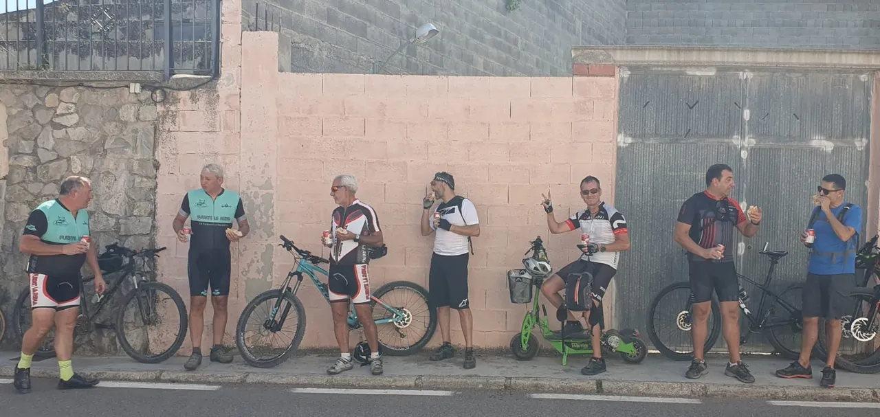Siete zorricos apoyados en el muro con las bicis, almorzando