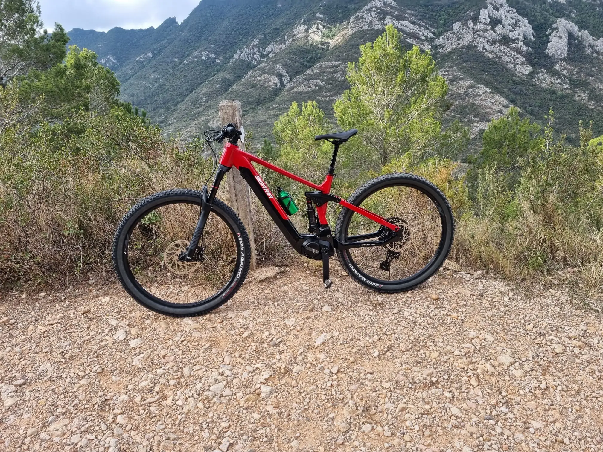 Una e-bike roja apoyada en un poste, esperando