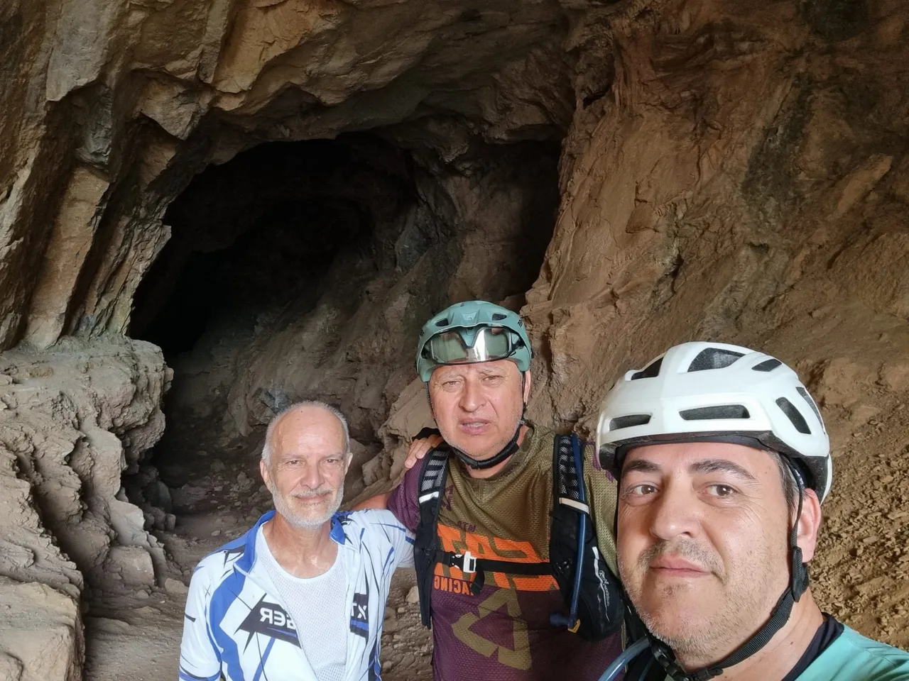 Tres zorricos posando en la boca de una cueva de arenisca